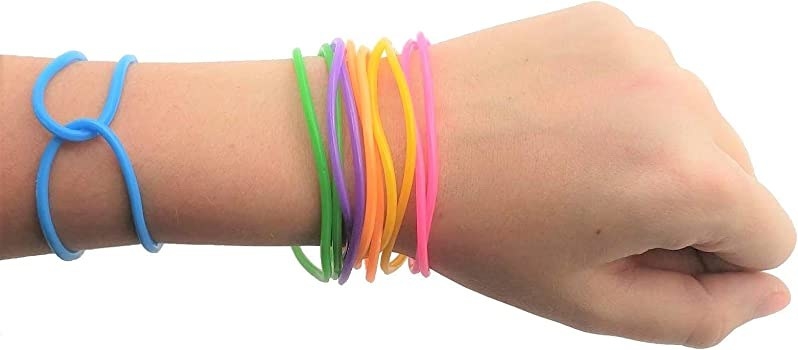 Someone with their arm out. Their wrist is adorned with several jelly bracelets.