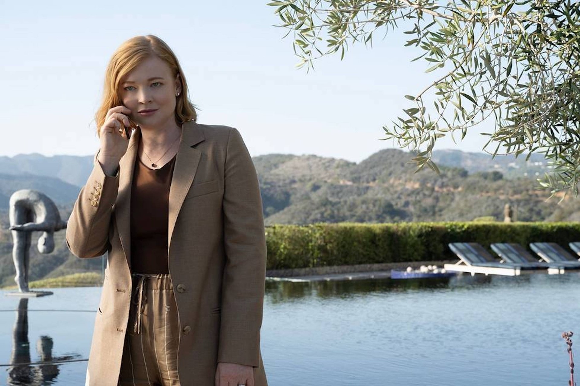 sarah snook as Shiv speaking on the phone while standing next to a pool in a scene from succession
