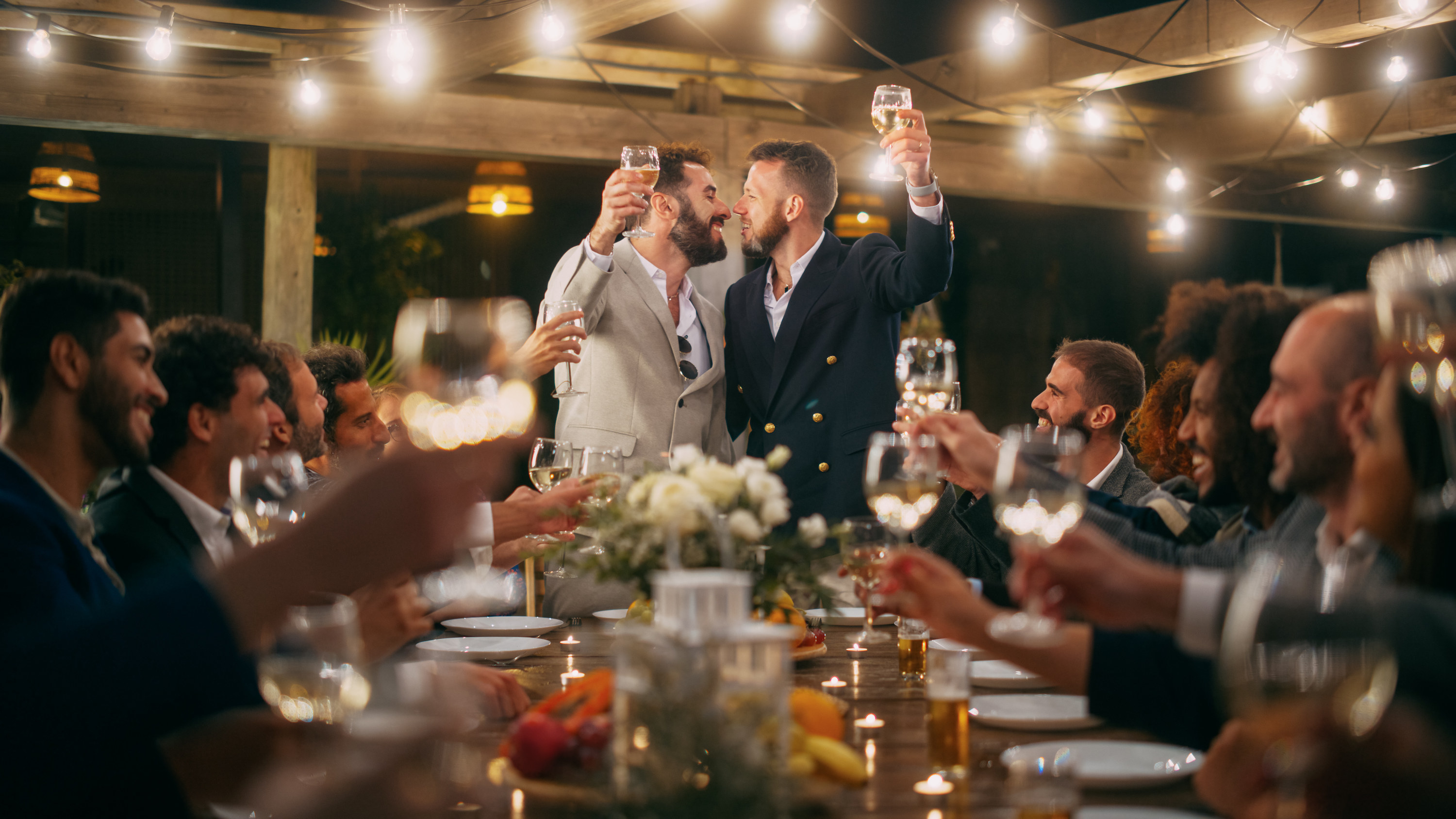 Two men kiss during a toast at their wedding reception