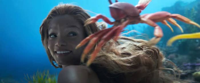 Halle Bailey as Ariel swimming with sebastian the crab