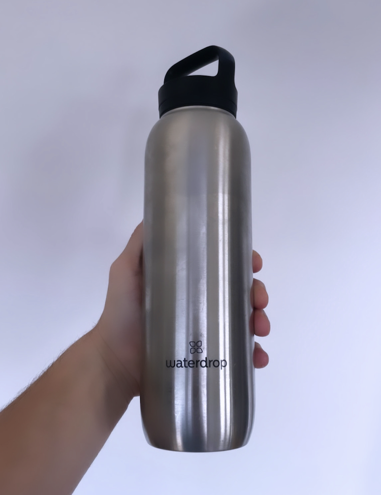 a man holds a large stainless steel Waterdrop waterbottle