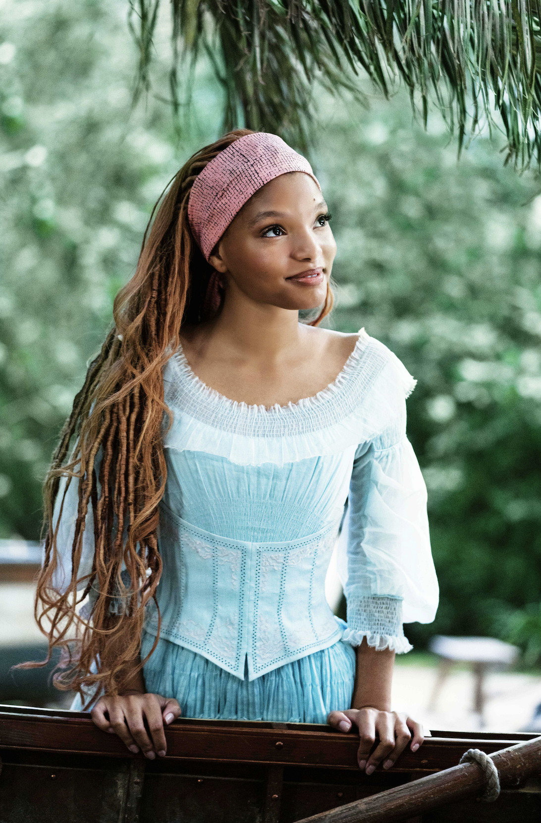 A closeup of halle as ariel with her long hair as she stands by a boat