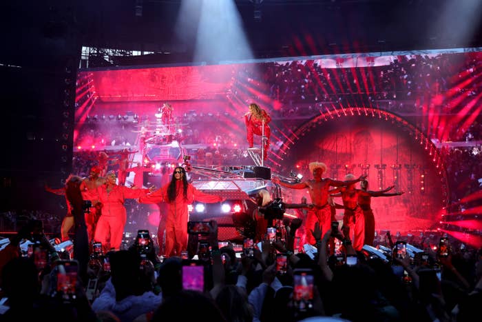 Blue stands in front of dancers while Beyonce is on an elevated platform in the background
