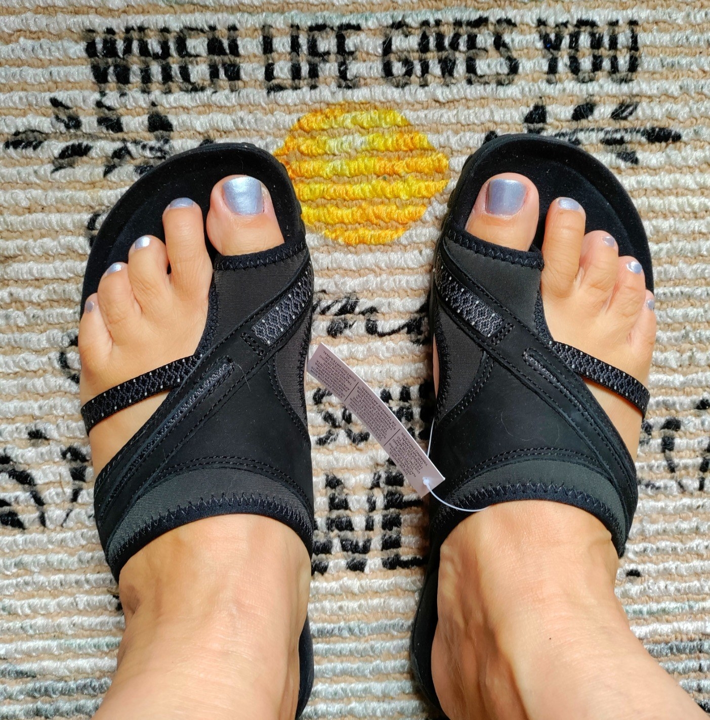 a reviewer wearing black sandals with blue pedicure
