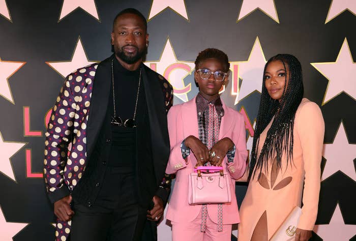 Dwyane Wade and Gabrielle Union pose for photographers at a red carpet event with Zaya in between them