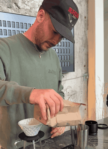 A gif of the coffee shop owner pouring coffee beans into a cup