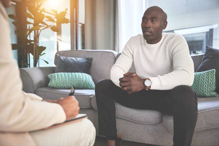 A man talks with a therapist while she writes down notes