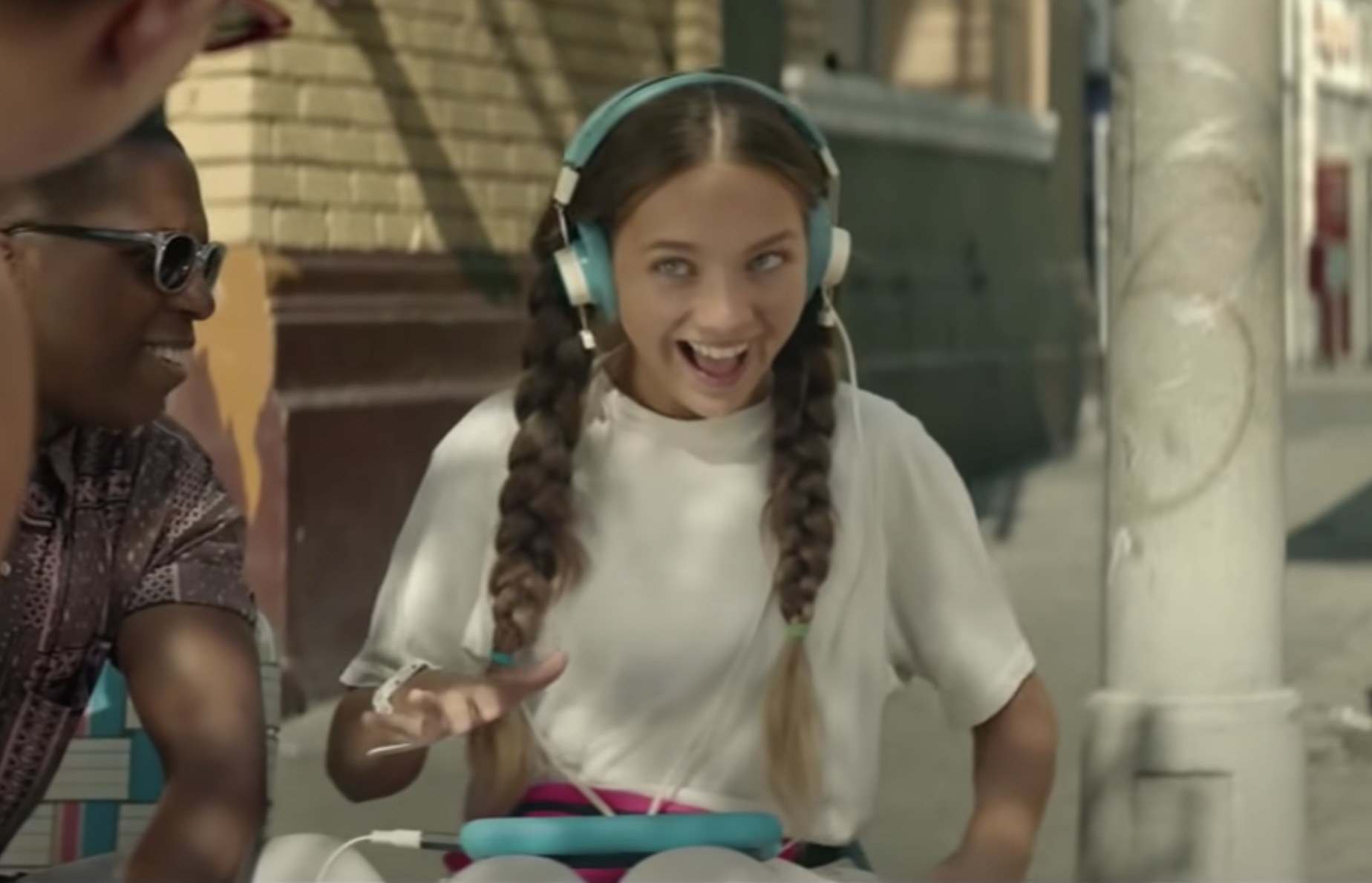 Maddie in the movie wearing headphones and holding a tablet
