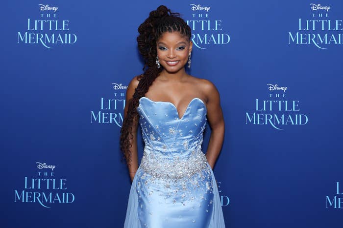 Halle Bailey smiles on the red carpet while wearing a strapless satin and embellished  dress