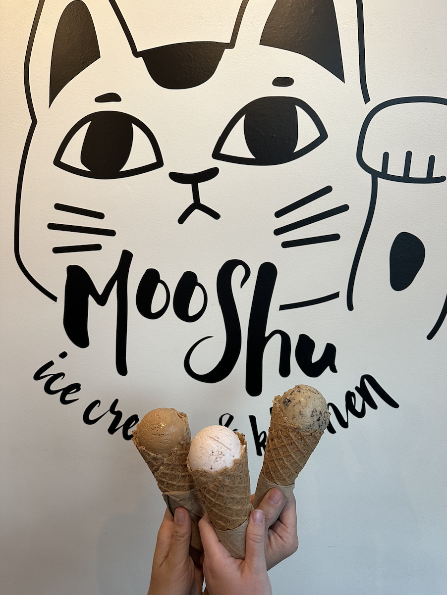 Three ice cream cones in front of a &quot;Moo Shu Ice Cream&quot; sign