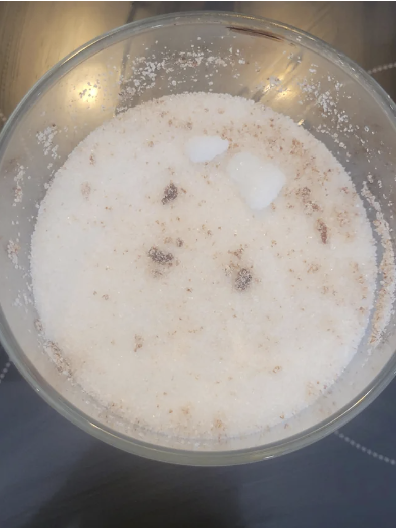 A bowl of sugar with brown particles throughout