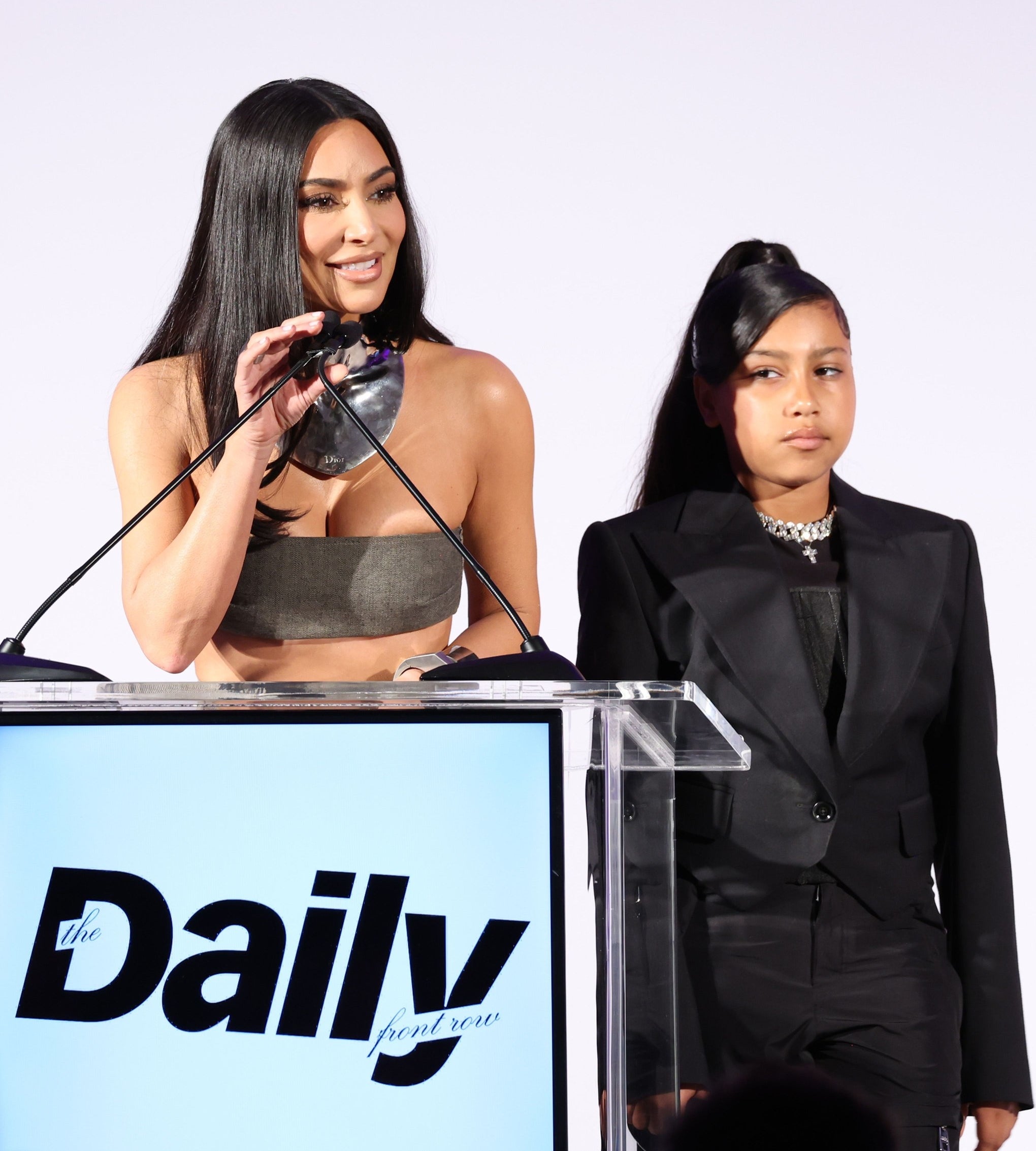 north standing next to kim as she speaks at a podium