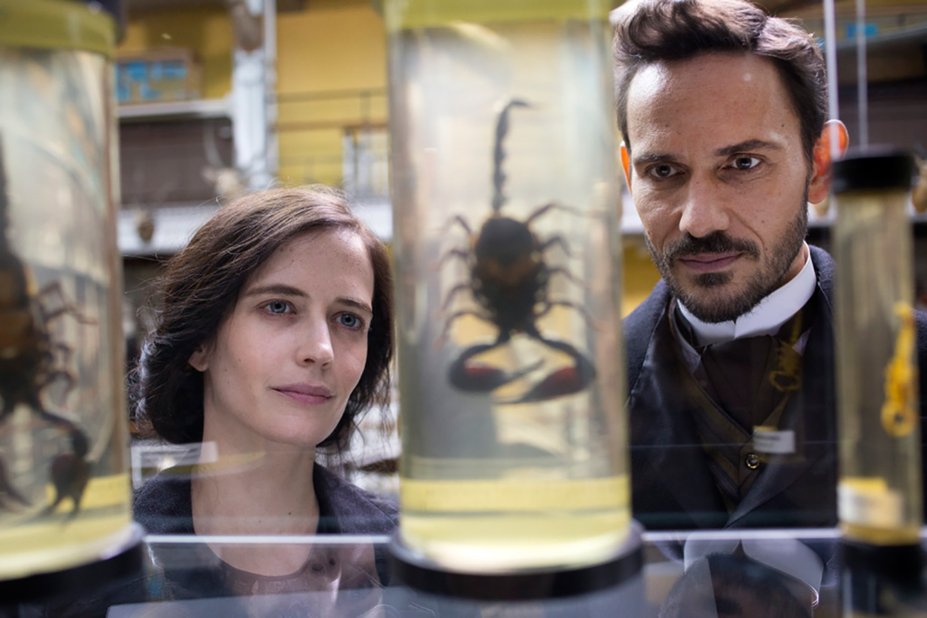 two people in a lab looking at a scorpion in a glass jar