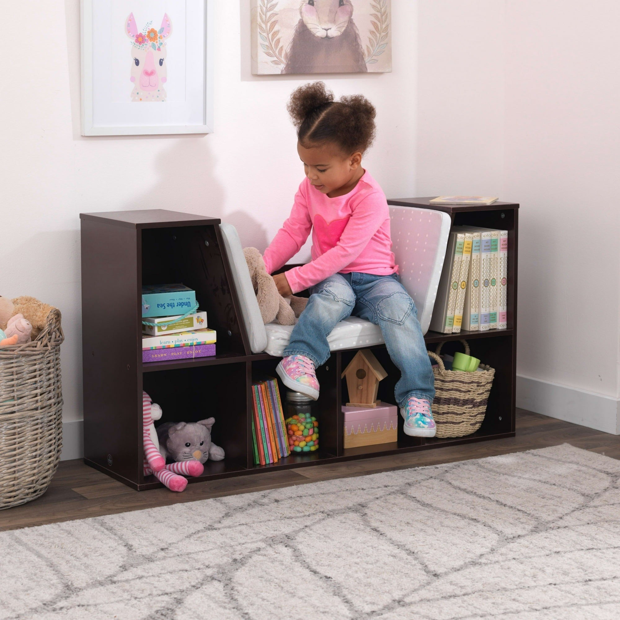 A little girl in her reading nook with a stuffed bunny.
