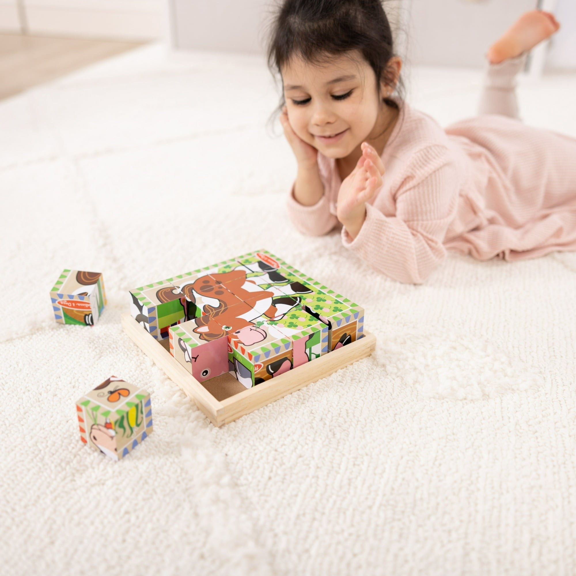 Little girl on the floor playing with the wooden block puzzle.