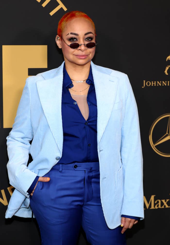 Raven-Symoné on the red carpet wearing a blouse, pants, and a blazer. She&#x27;s also wearing rounded sunglasses