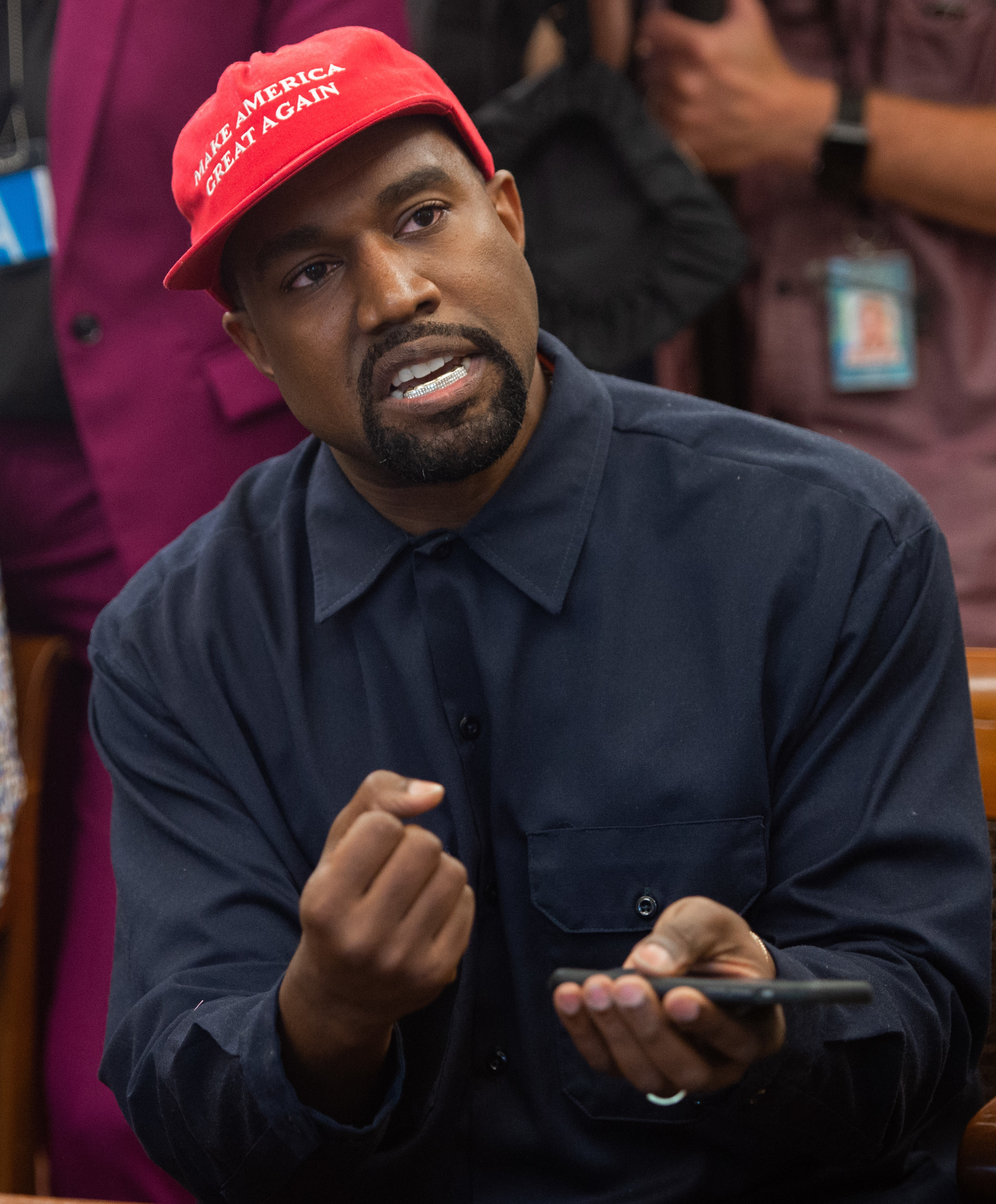 kanye with a maga hat and phone in hand