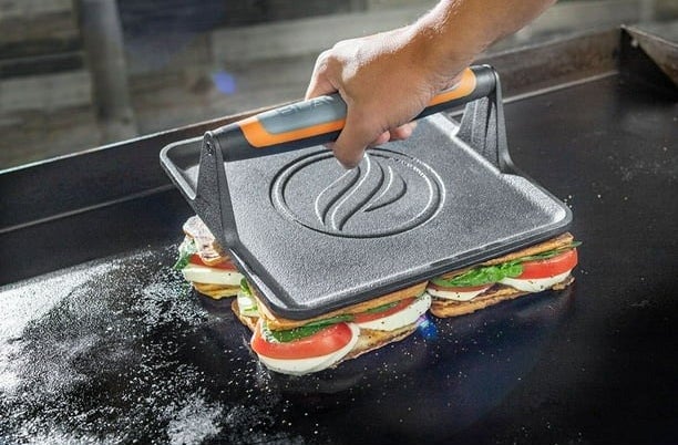 Model using griddle press on sandwiches on grill