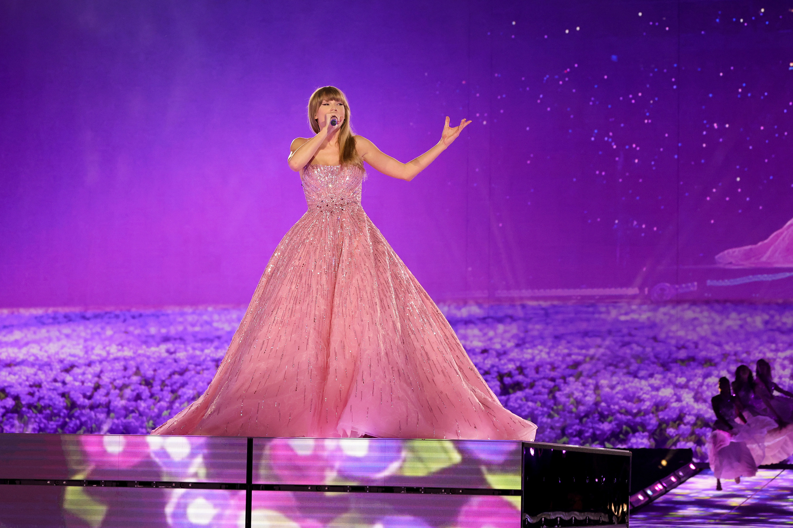 Taylor is wearing a strapless ball gown as she sings onstage