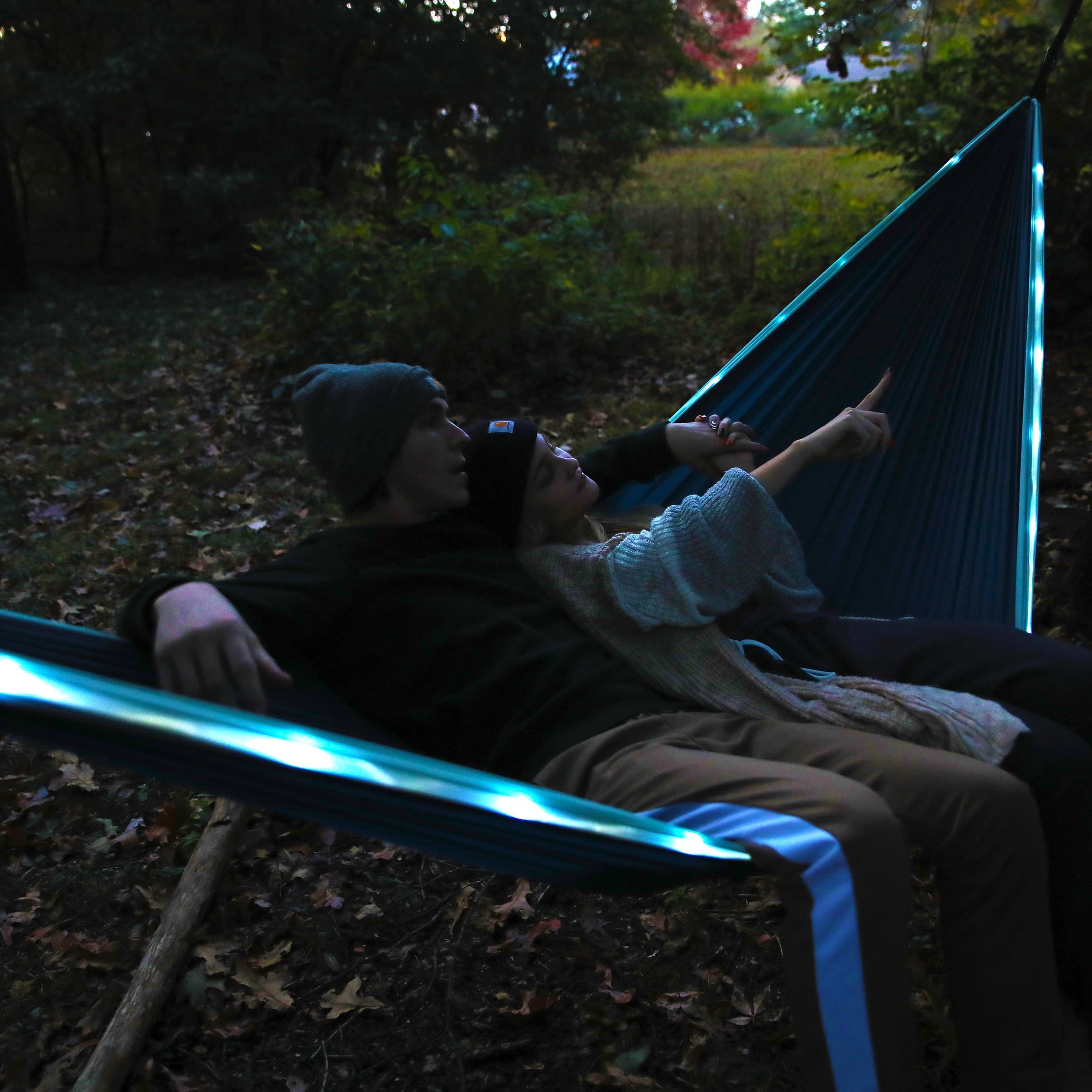 Two models sitting in hammock with blue LED lights around it