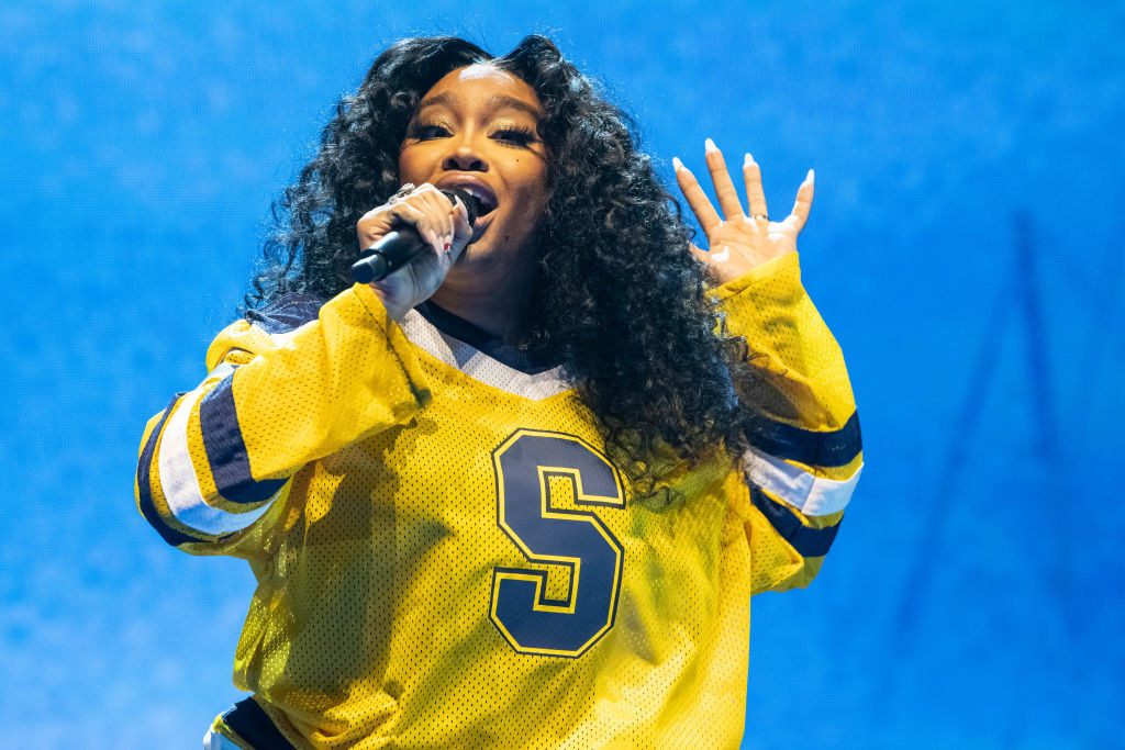 SZA singing onstage while wearing a s jersey with the letter &#x27;S&#x27; on the front