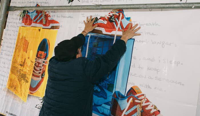 A worker applies a wheatpaste poster of the Unheardof x Adidas Rivalry Low to a scaffold in New York City in May