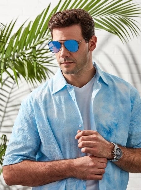 Model wearing black framed aviator sunglasses with blue lens