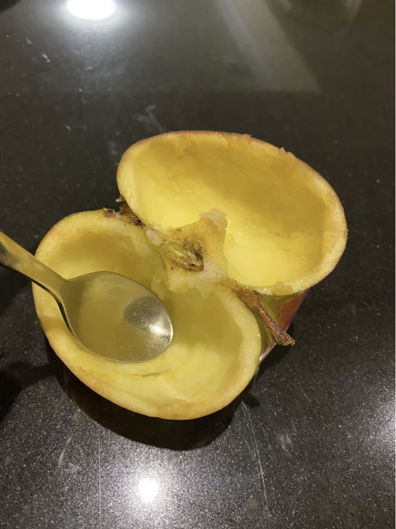 An apple with the inside scooped out with a spoon