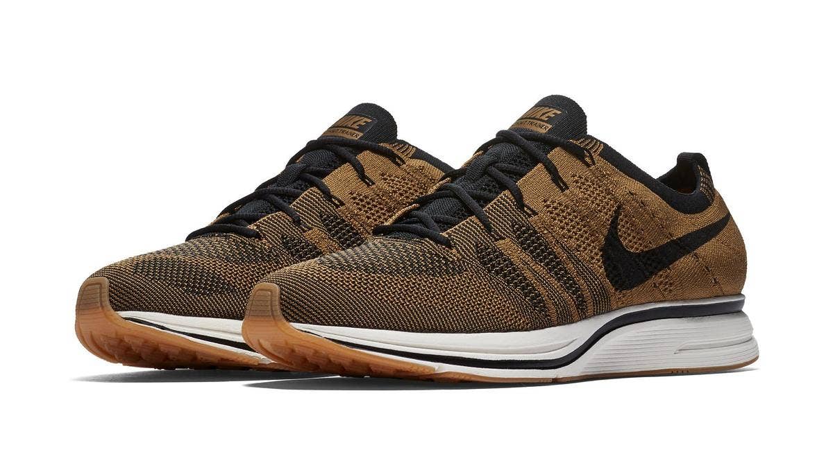 The Nike Flyknit Trainer is available now in a 'Golden Beige/Black/Gum Light Brown' colorway featuring a golden beige knit upper and a gum rubber outsole.