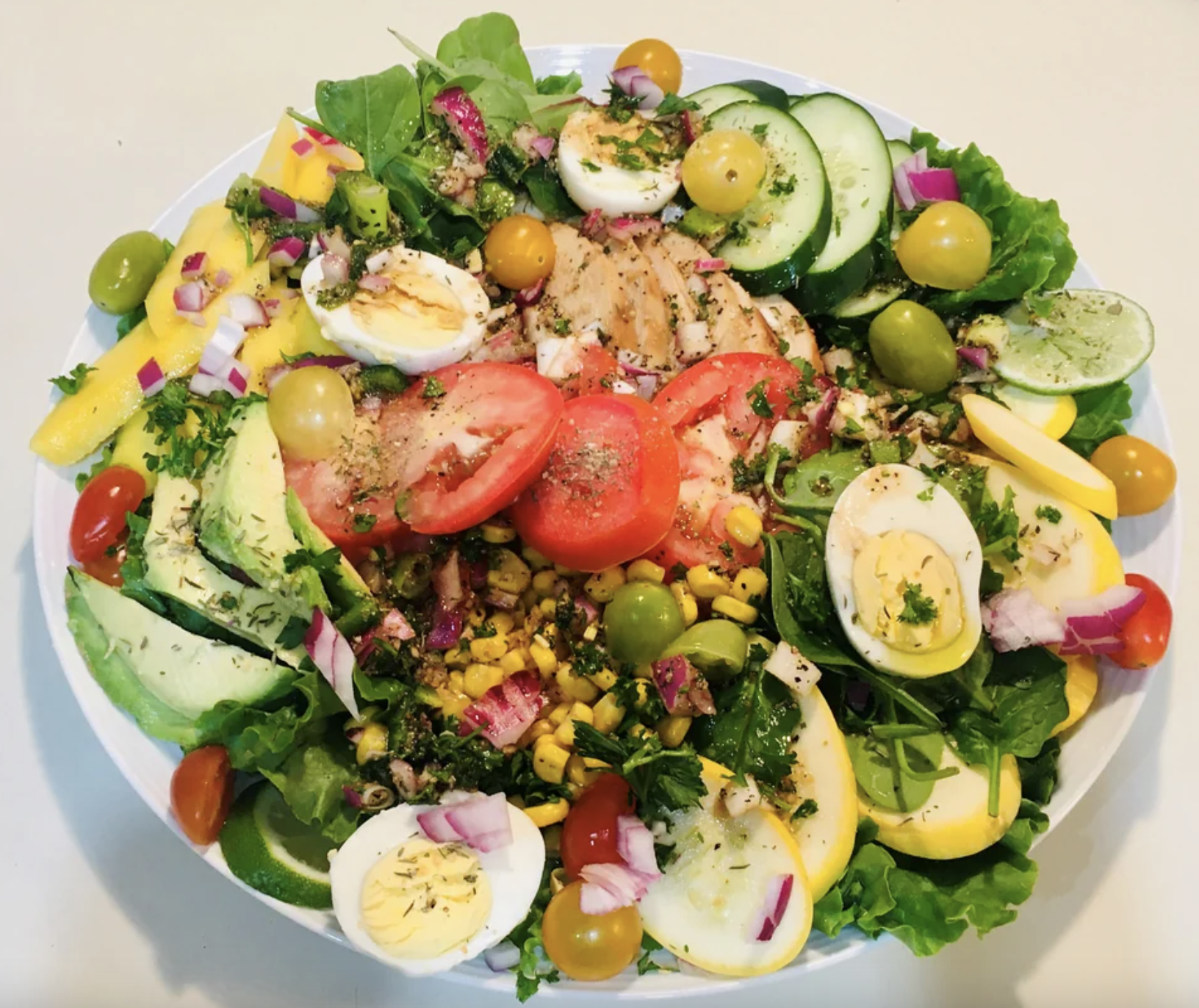 big bowl of salad with eggs tomatos avocado and more veggies