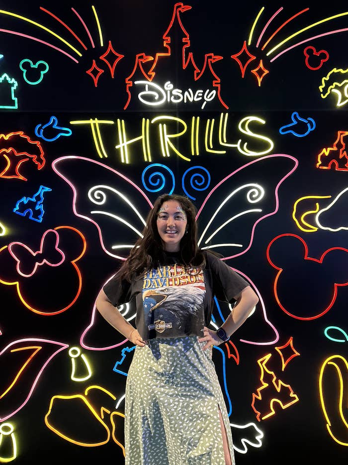 Writer in front of a neon sign that says &quot;Disney Thrills&quot;