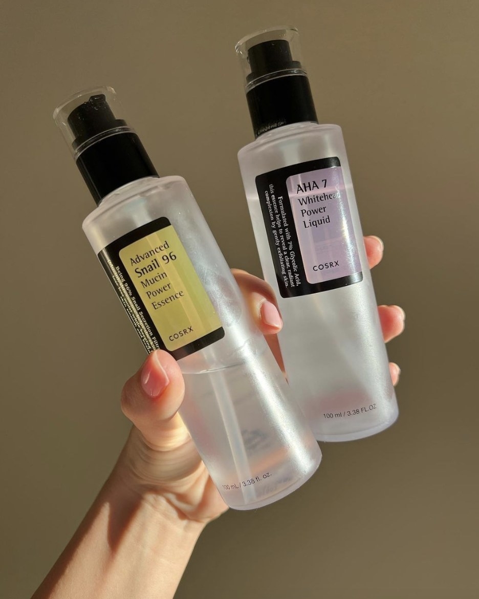 A person holding two bottles of skincare essence