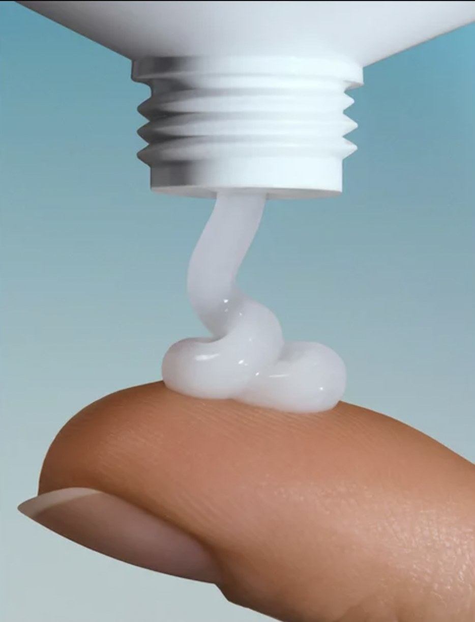 A person squeezing out face cream on their finger