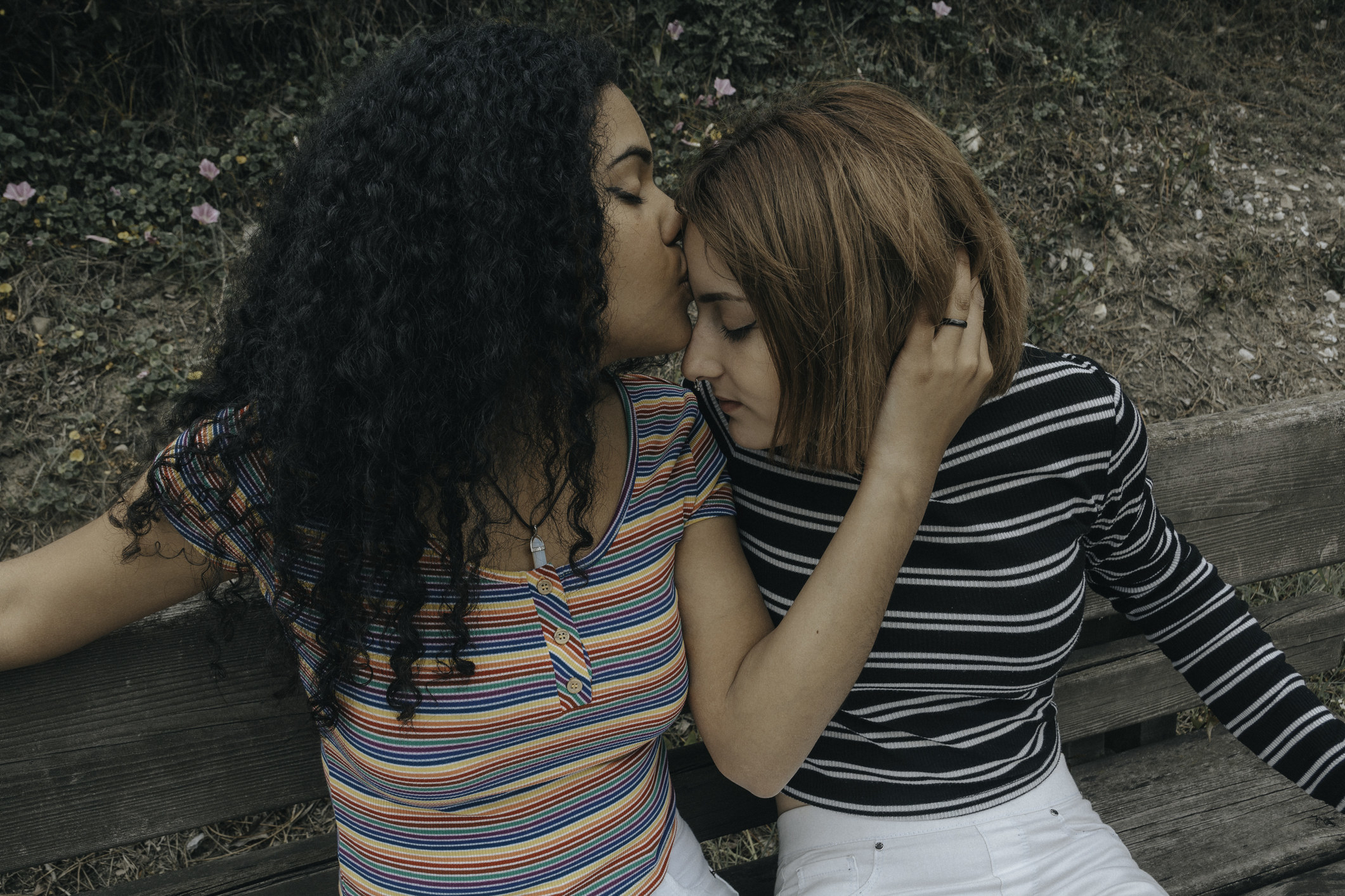Two teen lesbians kissing on a bench