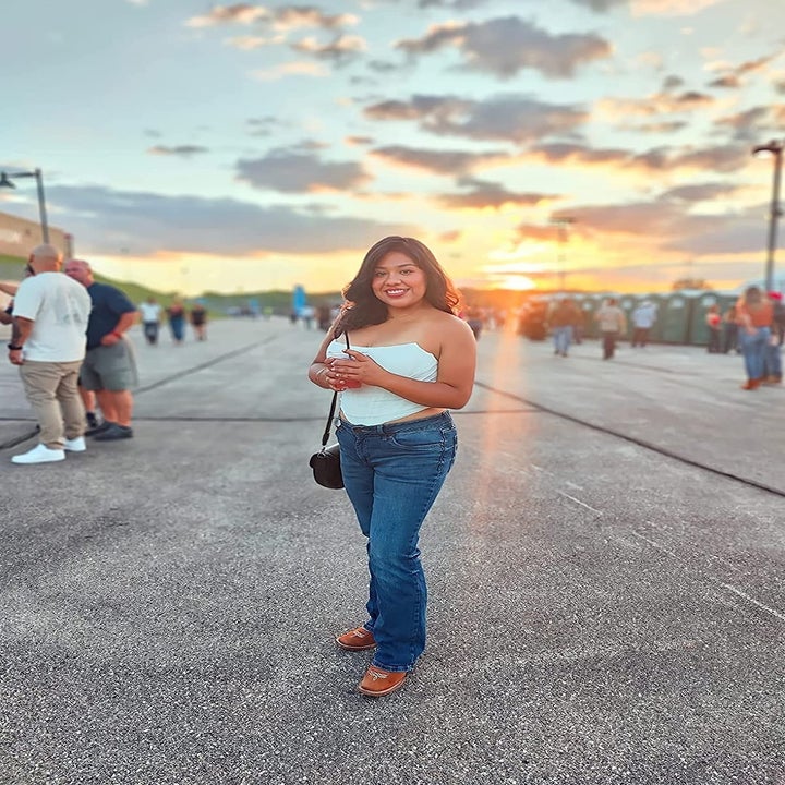 reviewer wearing white strapless corset top with low-rise jeans