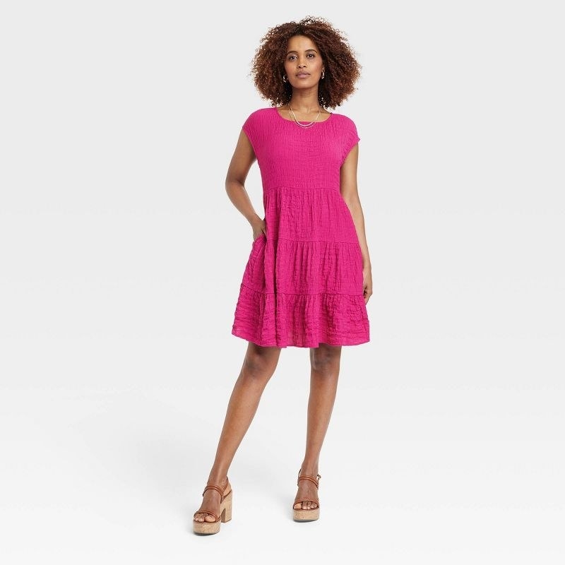 A model wearing a bright pink dress with brown shoes