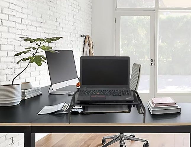 the black mesh monitor stand with a laptop on a black desk