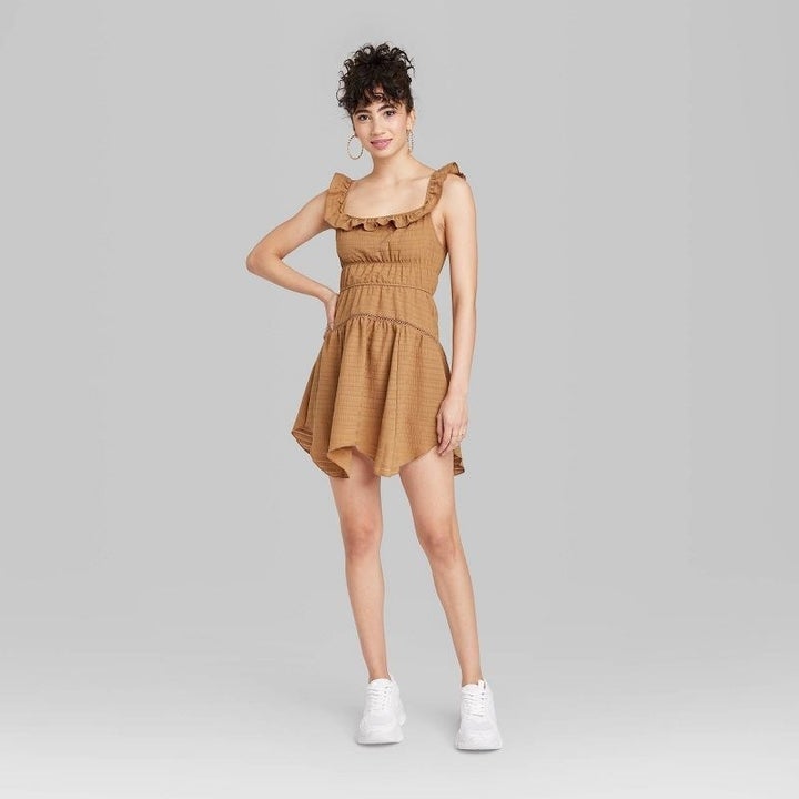 Model wearing tan color ruffle mini dress with white sneakers