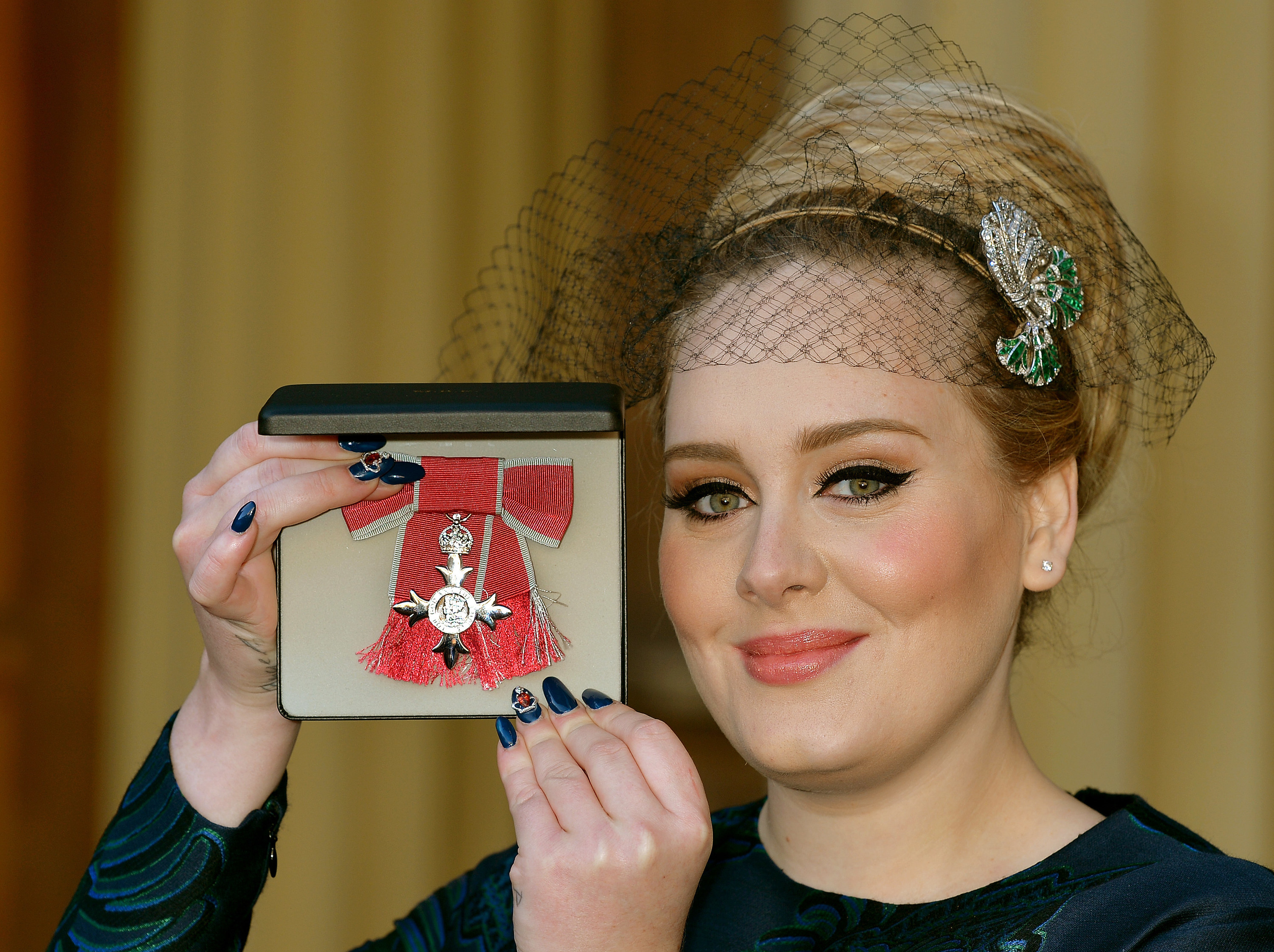 Adele holding her OBE medal