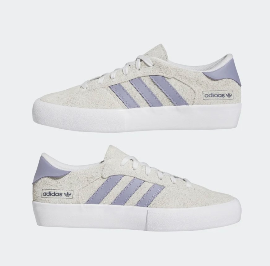 A pair of cream suede shoes with lavender stripes