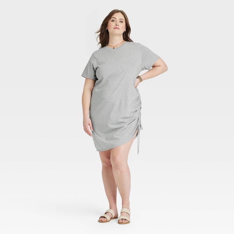 A model wearing a grey tee shirt dress with white shoes