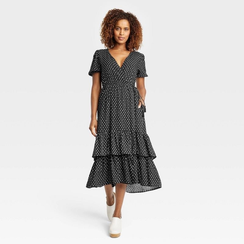 Model wearing black wrap dress with white polka dots