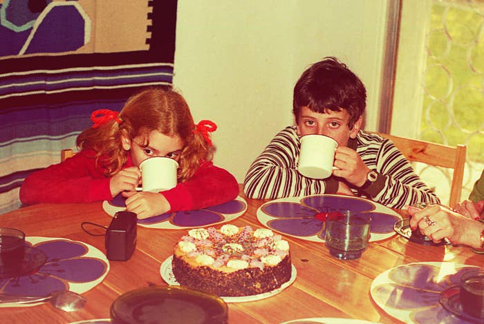 Kids drinking from mugs at the dinner table with a cake in front of them