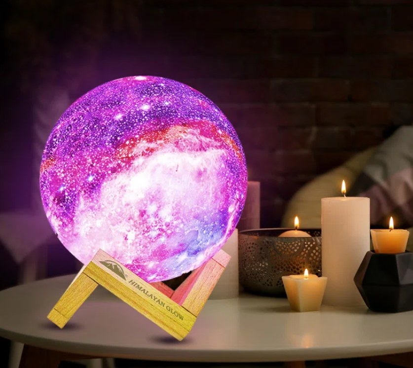 The galaxy moon lamp lit up purple on a coffee table