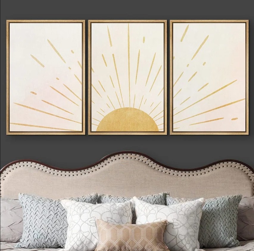 The three sunshine wall prints placed over a bed