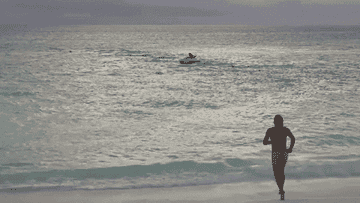 person running naked into the ocean