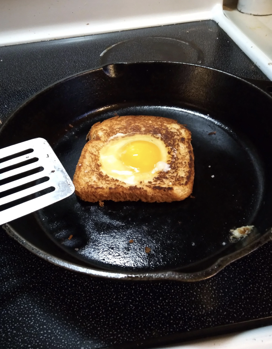 Egg in a hole cooking in a skillet.
