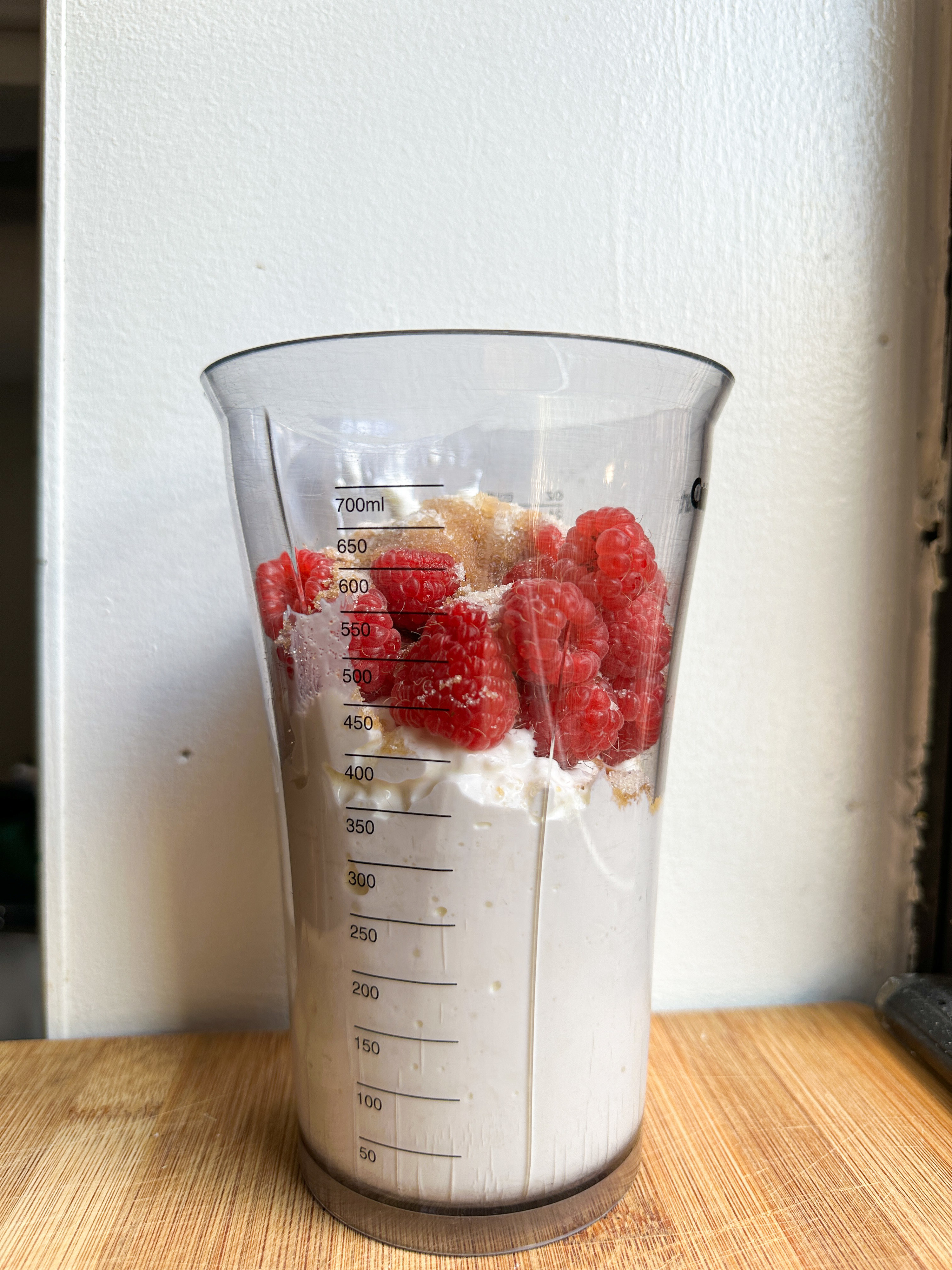 blender cup with cottage cheese, brown sugar, white sugar, raspberries, and vanilla extract