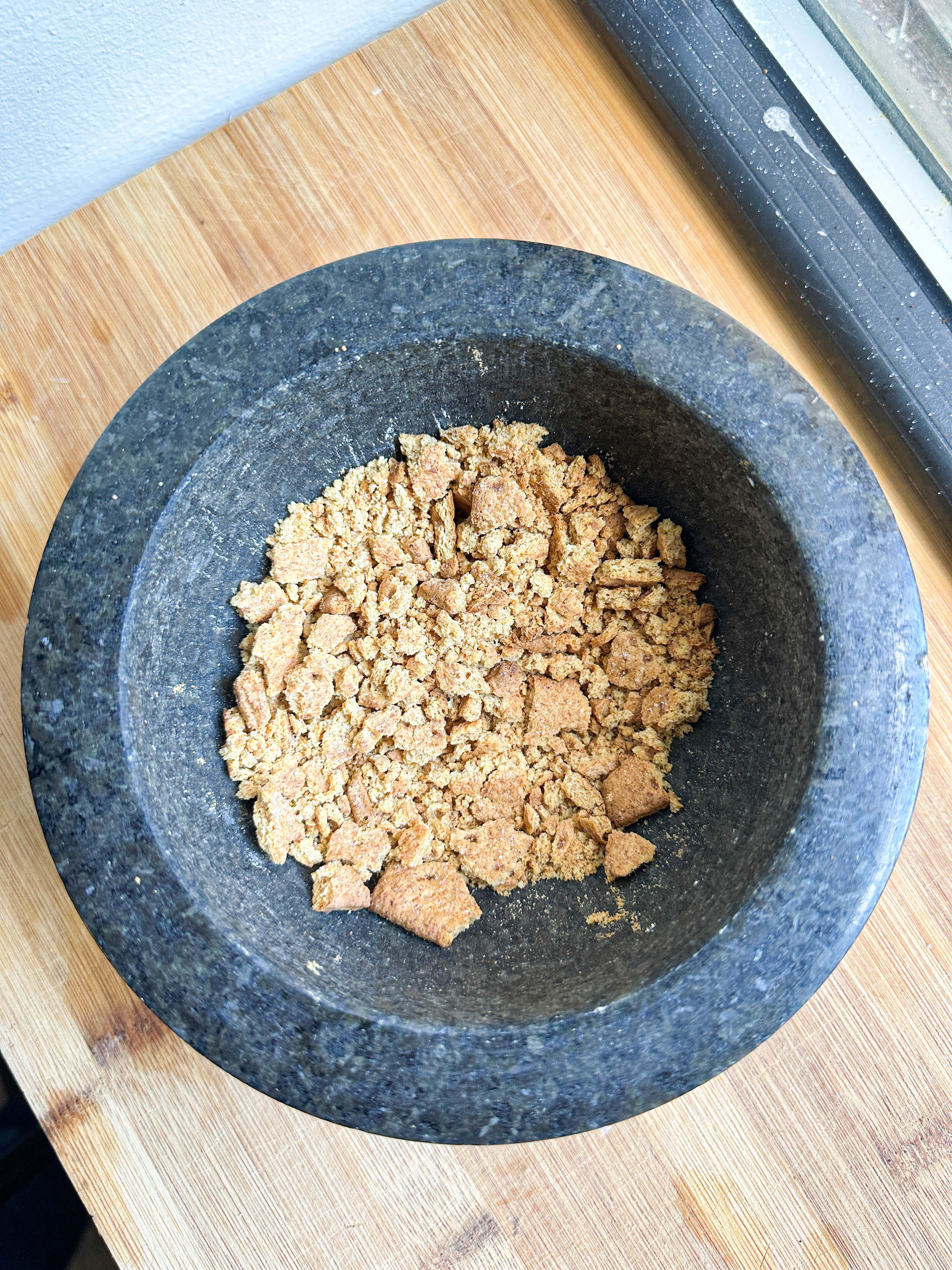 graham cracker pieces broken up in a mortal and pestle