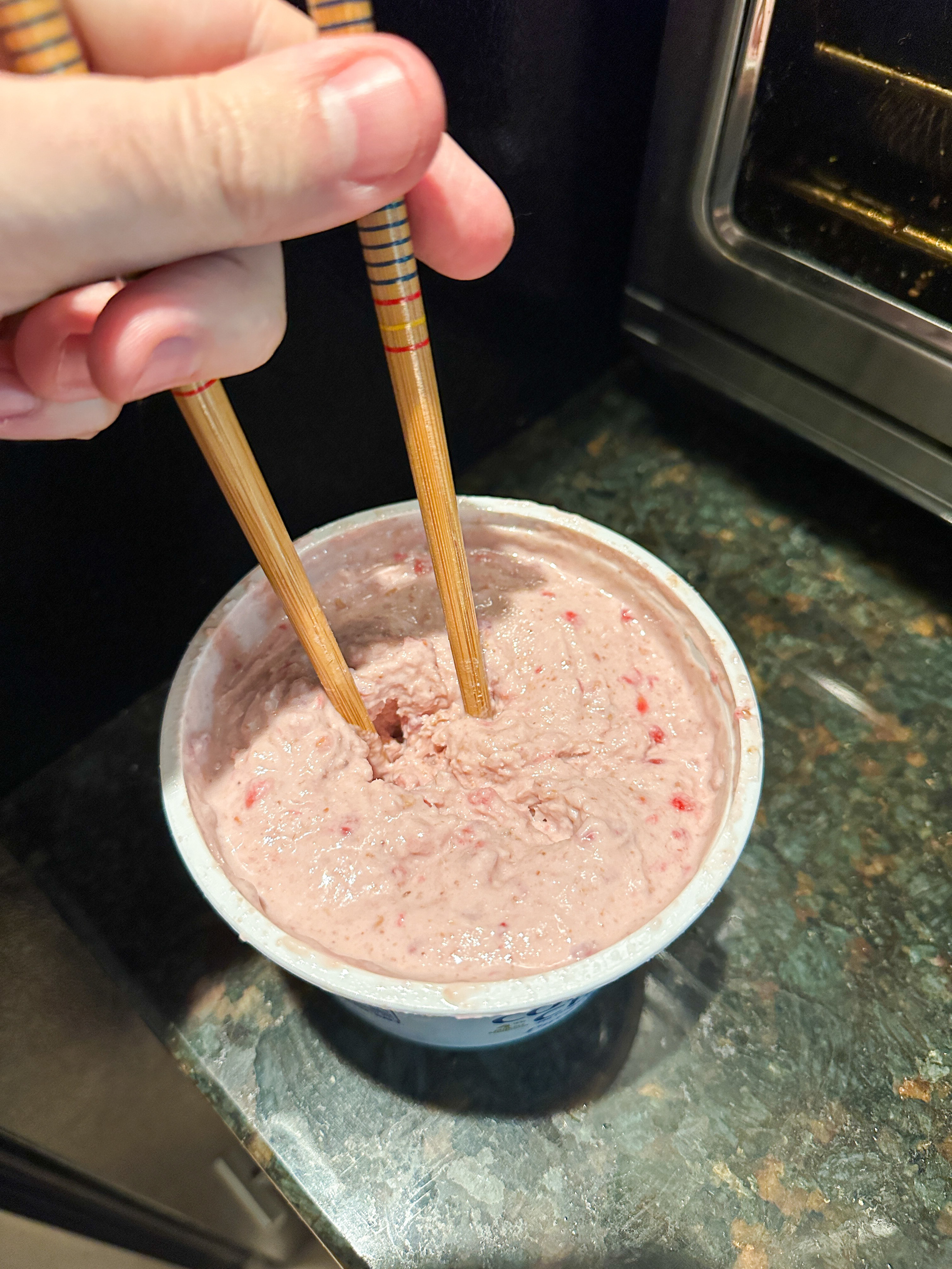 whisking around the ice cream in the container with two chop sticks